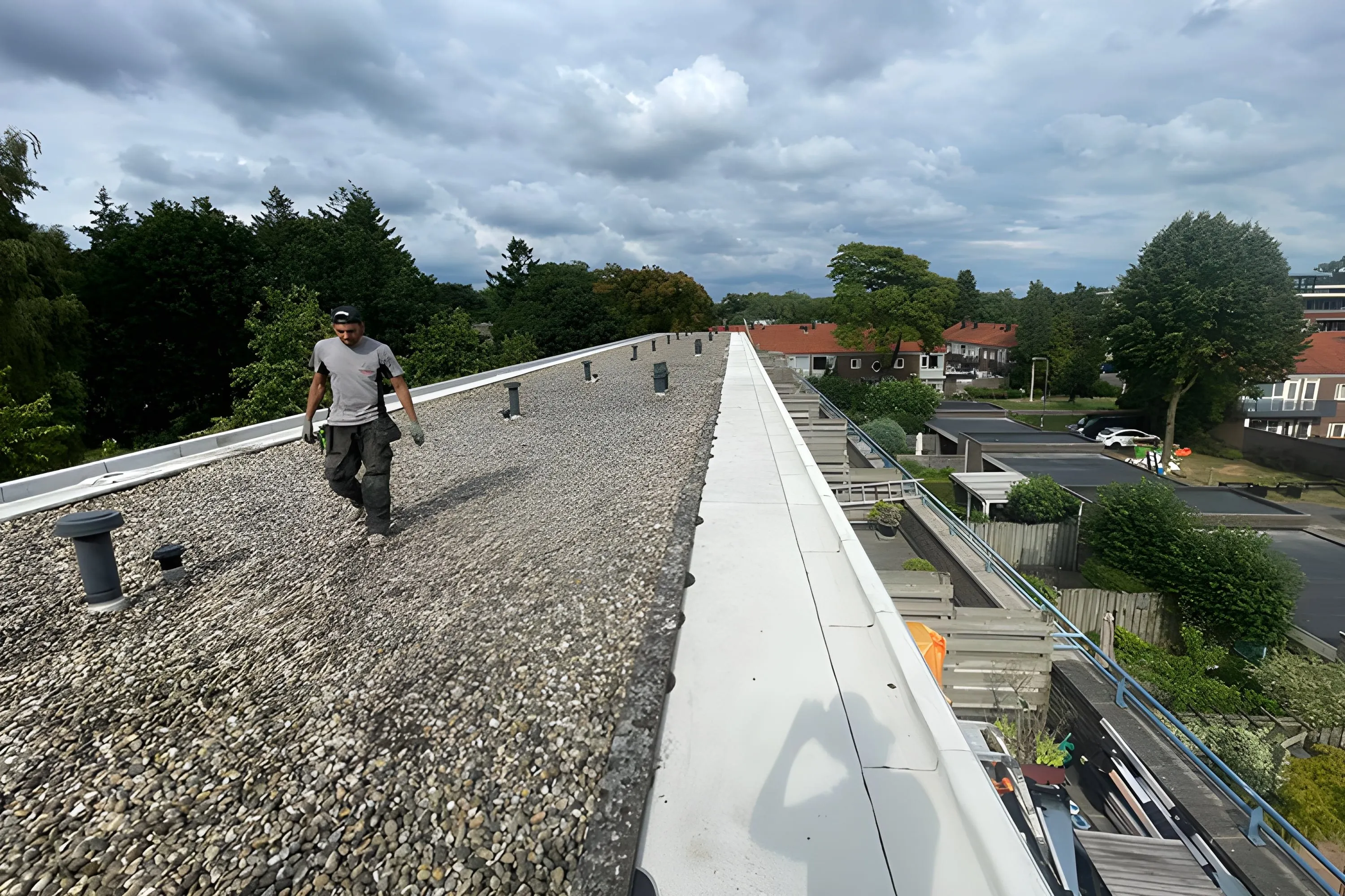 Dakdekker loopt een plat dak met grind en daktrim na tijdens onderhoud